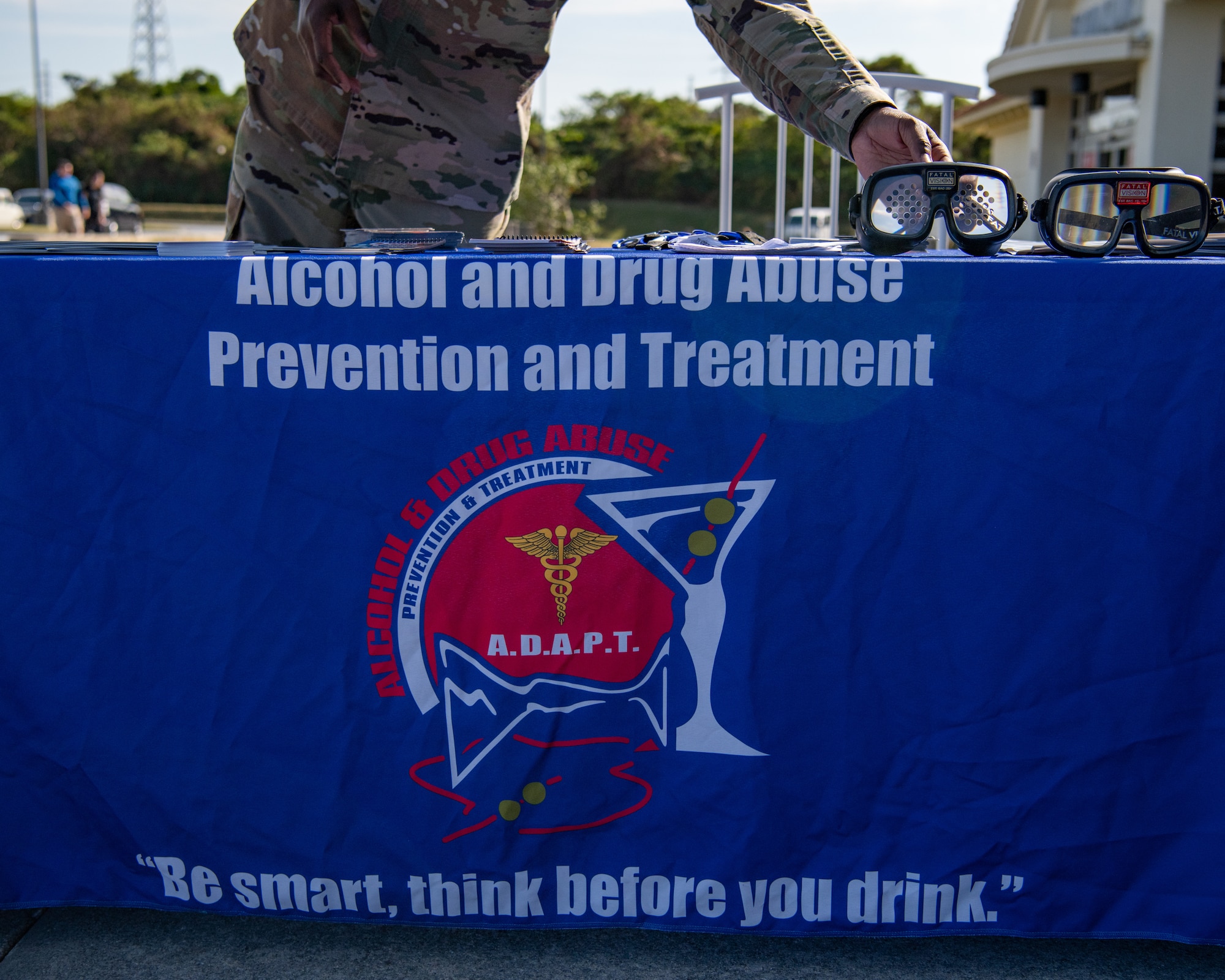 An Airman places vision impairment goggles on a table.