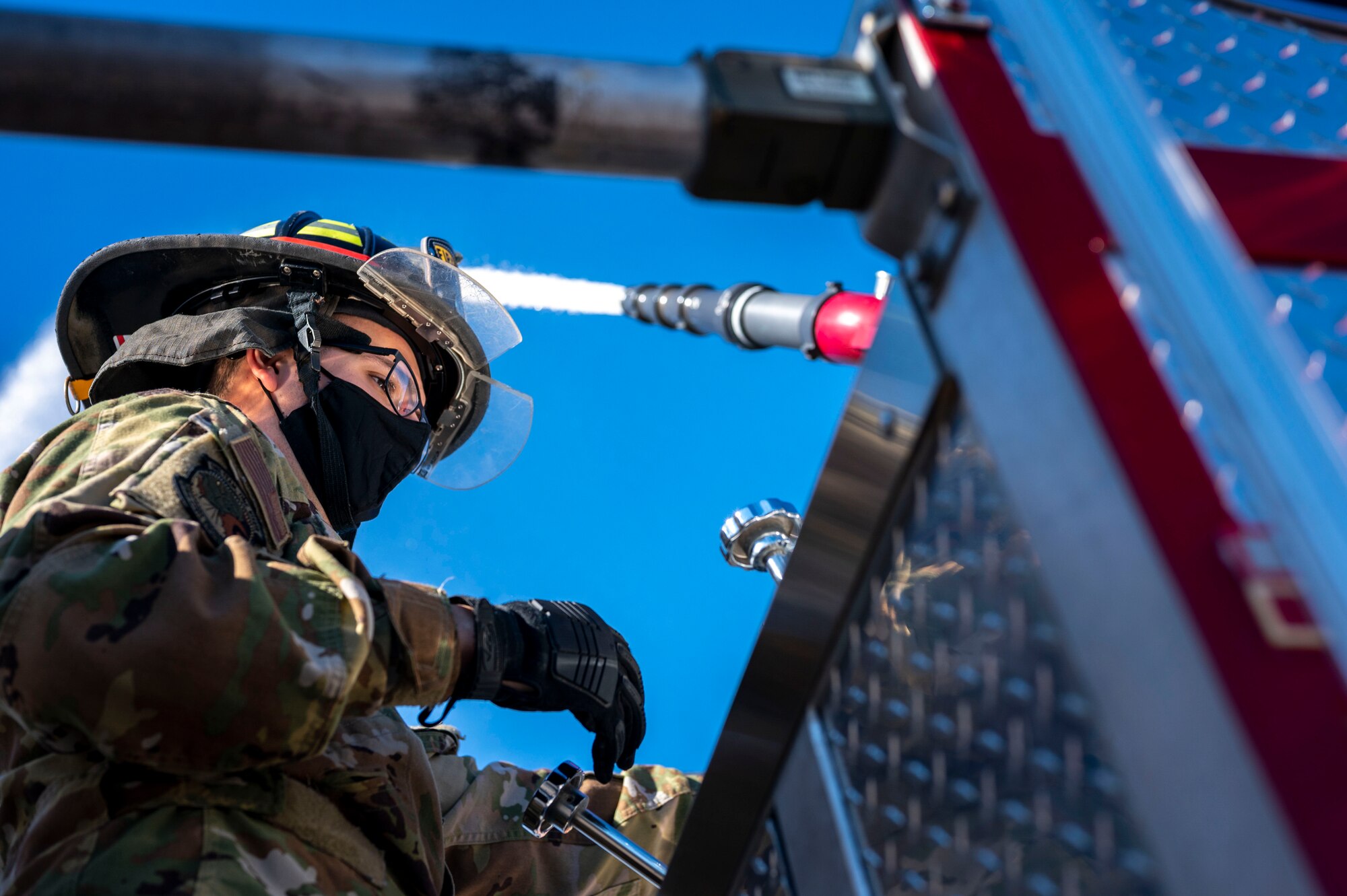 Firefighter sprays water using a deck gun