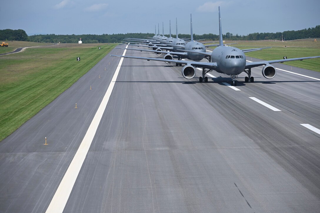 Several large aircraft are lined up on a runway.