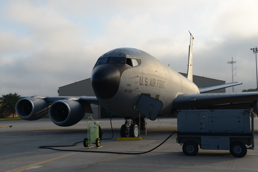 A large military aircraft sits on a concrete slab.