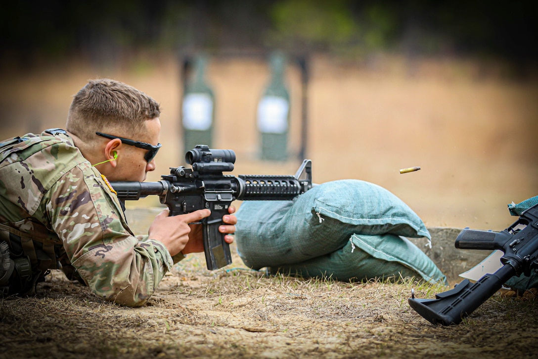 An Army ROTC cadet fires a weapon while laying on the ground.