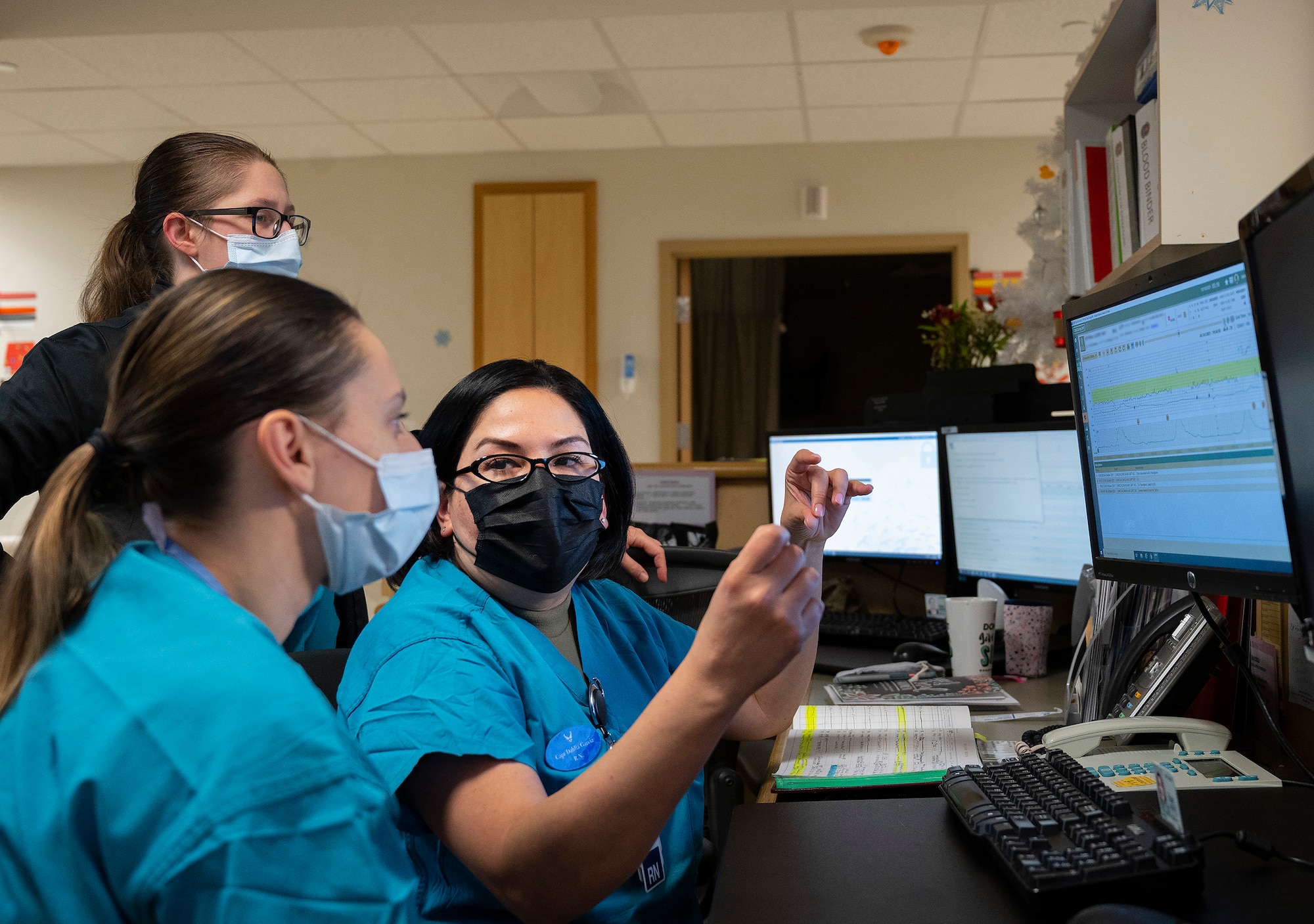 Capt. Dahlia Garcia (right), 88th Inpatient Operations Squadron charge nurse, works with 2nd Lt. Marjorie Zuber (foreground), a new Air Force nurse, at 5:20 a.m. during their Dec. 16, 2021, night shift at Wright-Patterson Medical Center’s Labor and Delivery Ward as Capt. Breanna Swartout looks on. Garcia called up some of the ward’s case histories to use as an example for things Zuber should look out for. (U.S. Air Force photo by R.J. Oriez) (Part of the screen was blurred for privacy reasons.)