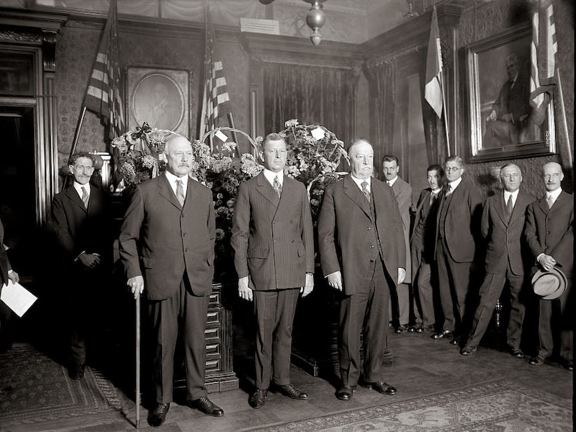 Three men in suits pose for photo.