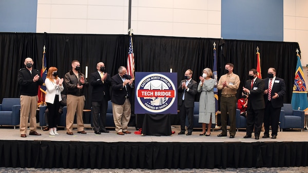 Group of 10 officials pose with a logo on an easel