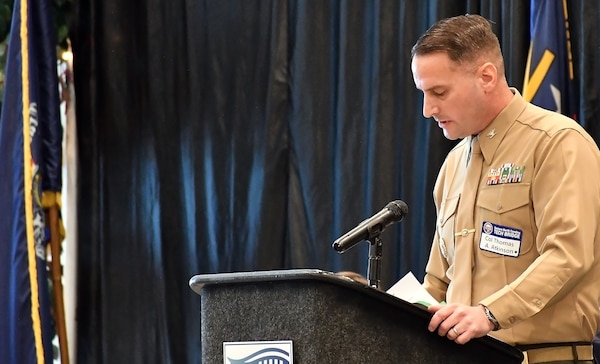 Marine Colonel Thomas A. Atkinson, Commanding Officer of Fleet Readiness Center East, speaks at a podium.