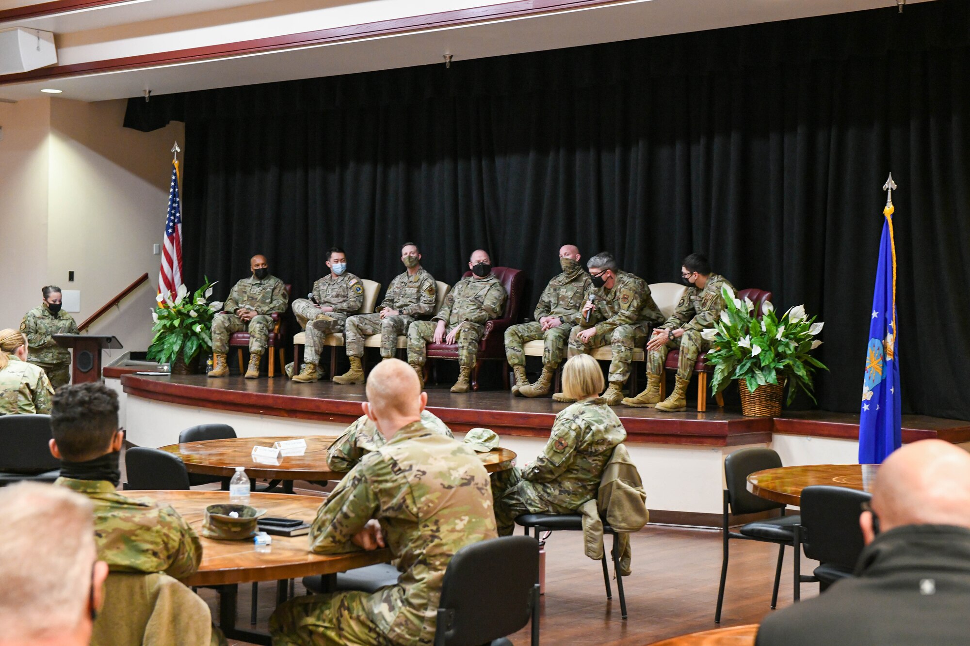 Airmen talk on stage while others listen