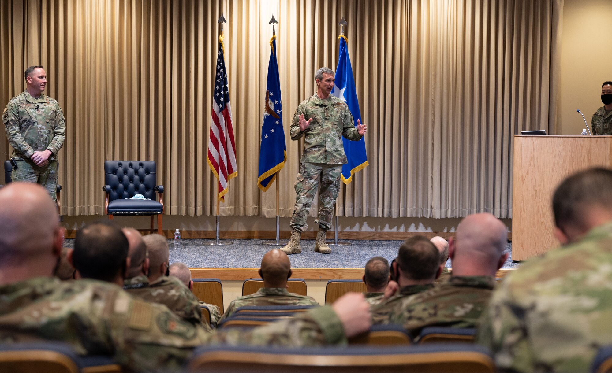 A man stands on a stage speaking to a crowd.