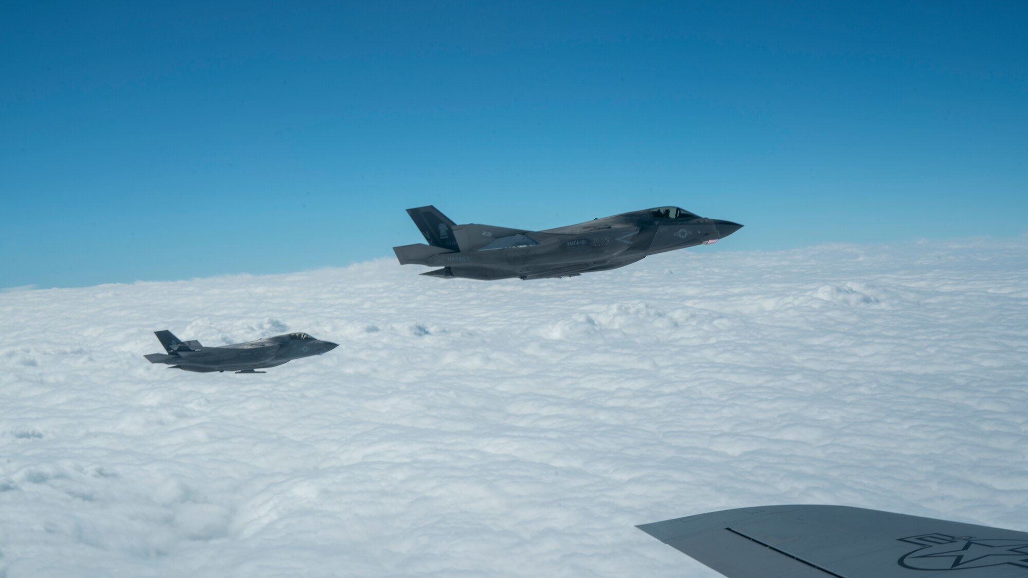 Two fighter jets fly off the wing of a plane