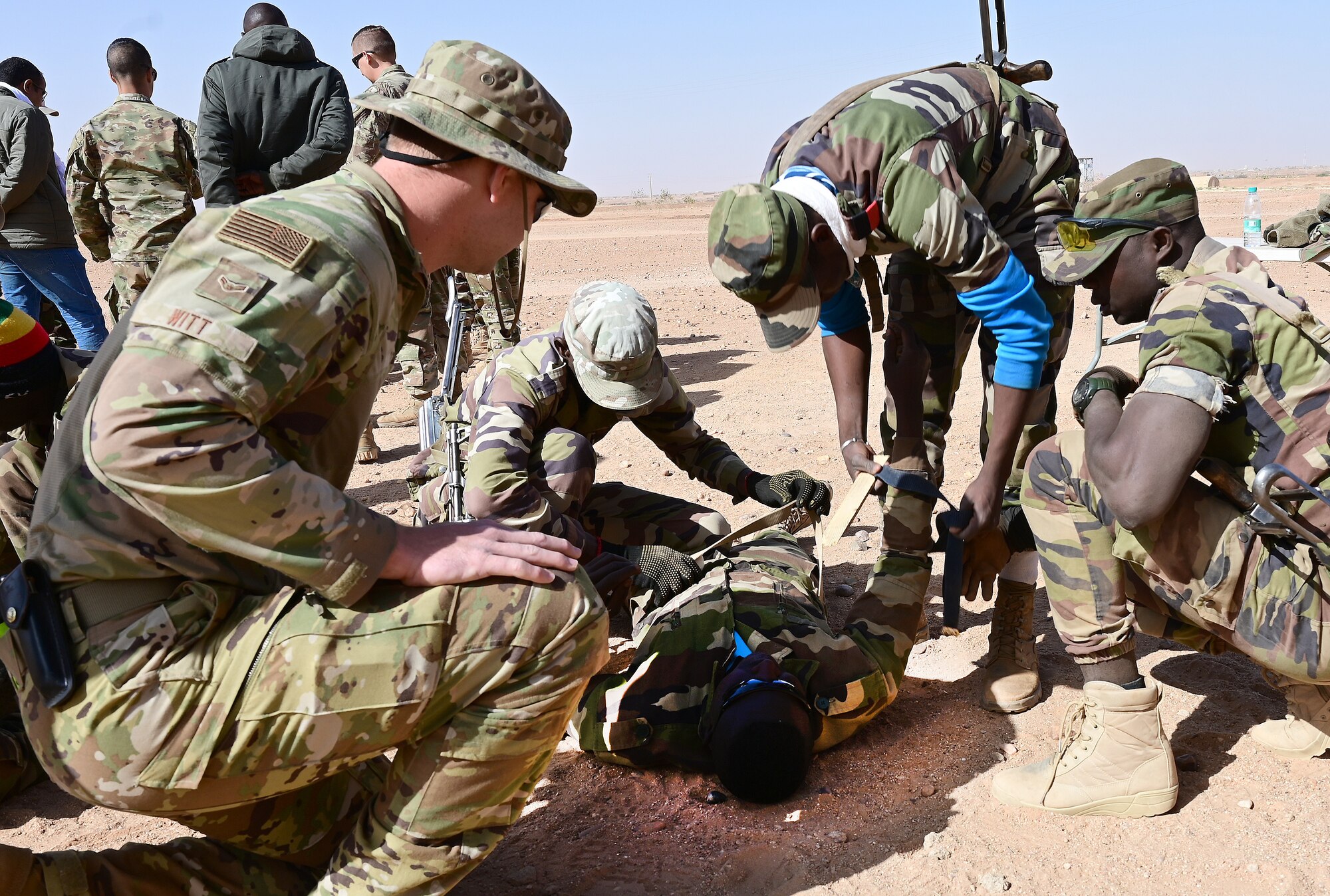 220121-F-EI771-0143
 	Airman 1st Class Jeremy Witt, 724th Expeditionary Air Base Squadron firefighter, observes the Nigerien Armed Forces (French language: Forces Armées Nigeriennes) members practicing splints and bandages during a combat lifesaving skills training at Nigerien Air Base 201, Agadez, Niger, Jan. 21, 2022.This training is part of an eight-week military operations course taught by the 409th Expeditionary Security Forces Squadron air advisors and 724th Expeditionary Air Base Squadron firefighters to strengthen defense capabilities, while enhancing the long-standing military-to-military partnerships with African nations. Training alongside our African partners forges strategic relationships, and builds the operational confidence to cohesively join forces anytime, anywhere. (U.S. Air Force photo by Tech. Sgt. Stephanie Longoria)