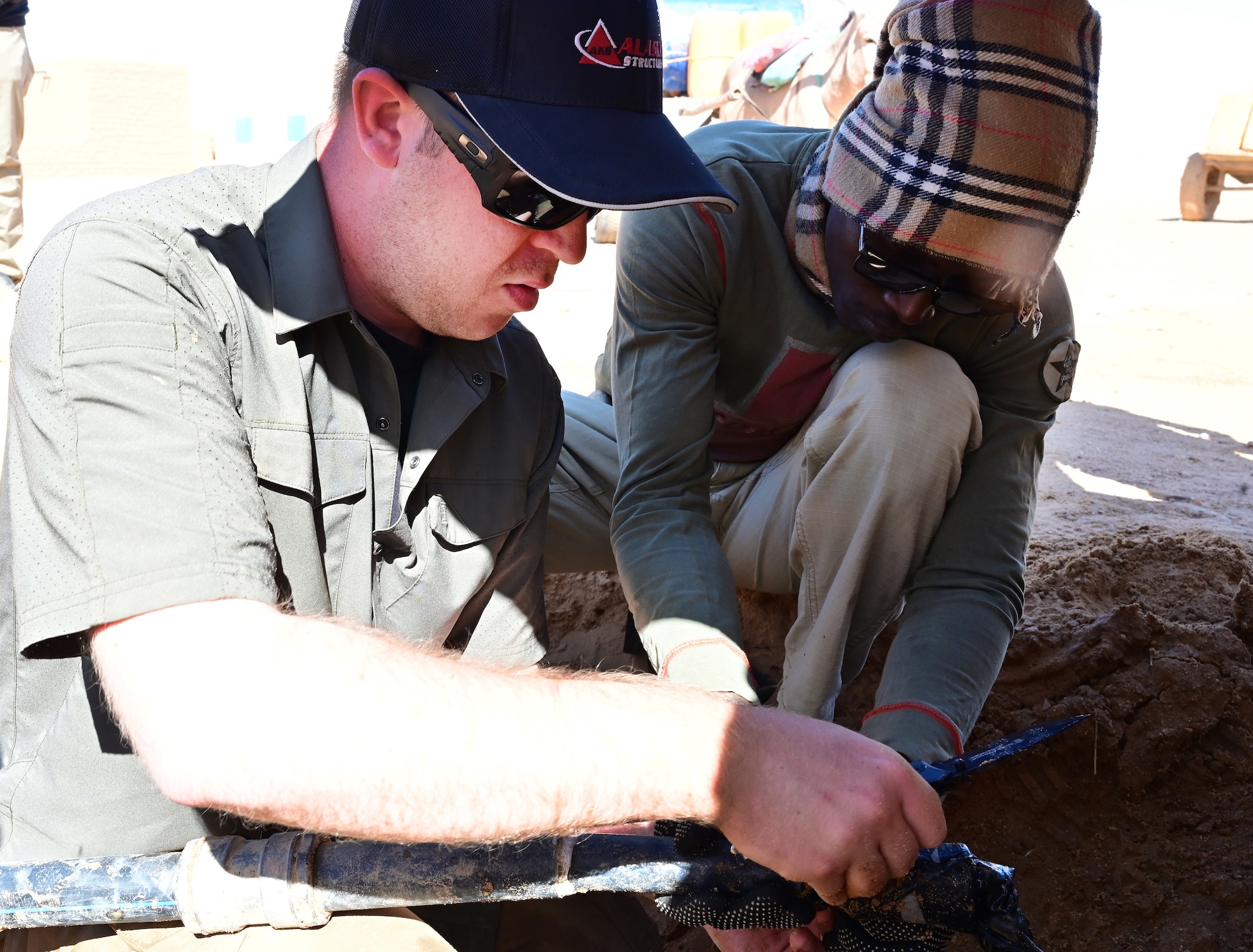 U.S. Air Force Staff Sgt. Forrest Hutchins, 724th Expeditionary Air Base Squadron civil engineering flight, teaches plumbing skills to Nigerien Armed Forces (French language: Forces Armées Nigeriennes) action civil military (ACM) member while repairing a waterline leaks in the village of Alwat, Agadez, Niger, Jan. 22, 2022. Joint projects with the FAN AMC increases future collaboration in Alwat and improves relationships between the civilian leaders, FAN and the U.S. (U.S. Air Force photo by Tech. Sgt. Stephanie Longoria)
