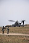 Soldiers from Task Force Lobos, 2nd Battalion, 2-227th Aviation Regiment, 1st Air Cavalry Brigade, 1st Cavalry Division, make their way back to the airfield headquarters as an AH-64D Apache attack helicopter prepares to depart, Jan. 27, Joint Multinational Readiness Center, Hohenfels Training Area, Germany. The 2-227th is participating in Allied Spirit 22, an exercise comprising over 5000 Soldiers from 15 nations that is designed to enable integration of the U.S. military and its allies in a competitive combat training environment. (U.S. Army Photo by Capt. Alun Thomas, 201st Theater Public Affairs Support Element)