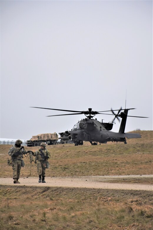 Soldiers from Task Force Lobos, 2nd Battalion, 2-227th Aviation Regiment, 1st Air Cavalry Brigade, 1st Cavalry Division, make their way back to the airfield headquarters as an AH-64D Apache attack helicopter prepares to depart, Jan. 27, Joint Multinational Readiness Center, Hohenfels Training Area, Germany. The 2-227th is participating in Allied Spirit 22, an exercise comprising over 5000 Soldiers from 15 nations that is designed to enable integration of the U.S. military and its allies in a competitive combat training environment. (U.S. Army Photo by Capt. Alun Thomas, 201st Theater Public Affairs Support Element)