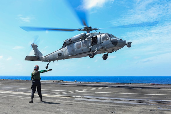 Aviation Structural Mechanic Airman Sydney Buckels, from Cleveland, directs an MH-60S Sea Hawk helicopter on the flight deck of the Nimitz-class aircraft carrier USS Abraham Lincoln (CVN 72).