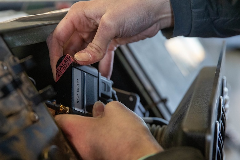 A Department of Defense contractor installs a Condition-Based Maintenance Plus (CBM+) data source collector into the dashboard of a Medium Tactical Vehicle Replacement (MTVR) at 2nd Transportation Battalion (TB), Combat Logistics Regiment 27, on Camp Lejeune, North Carolina, Feb. 1, 2022. CBM+ is a maintenance and supply strategy that integrates process improvement, failure data, and technology to influence maintenance actions, increase equipment availability, and improve fleet management. 2nd Transportation Battalion is the first unit in the Fleet Marine Force to install data loggers affiliated with CBM+. (U.S. Marine Corps photo by Lance Cpl. Jessica J. Mazzamuto)