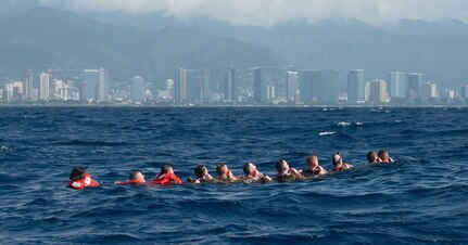 Wisconsin National Guard Airmen assigned to the 115th Fighter Wing Security Forces Squadron in Madison, Wisconsin, participate in water survival training off Honolulu Jan. 12, 2022. Forming a chain and counting off one-by-one ensured all members were accounted for before they swam together to a nearby life-raft.