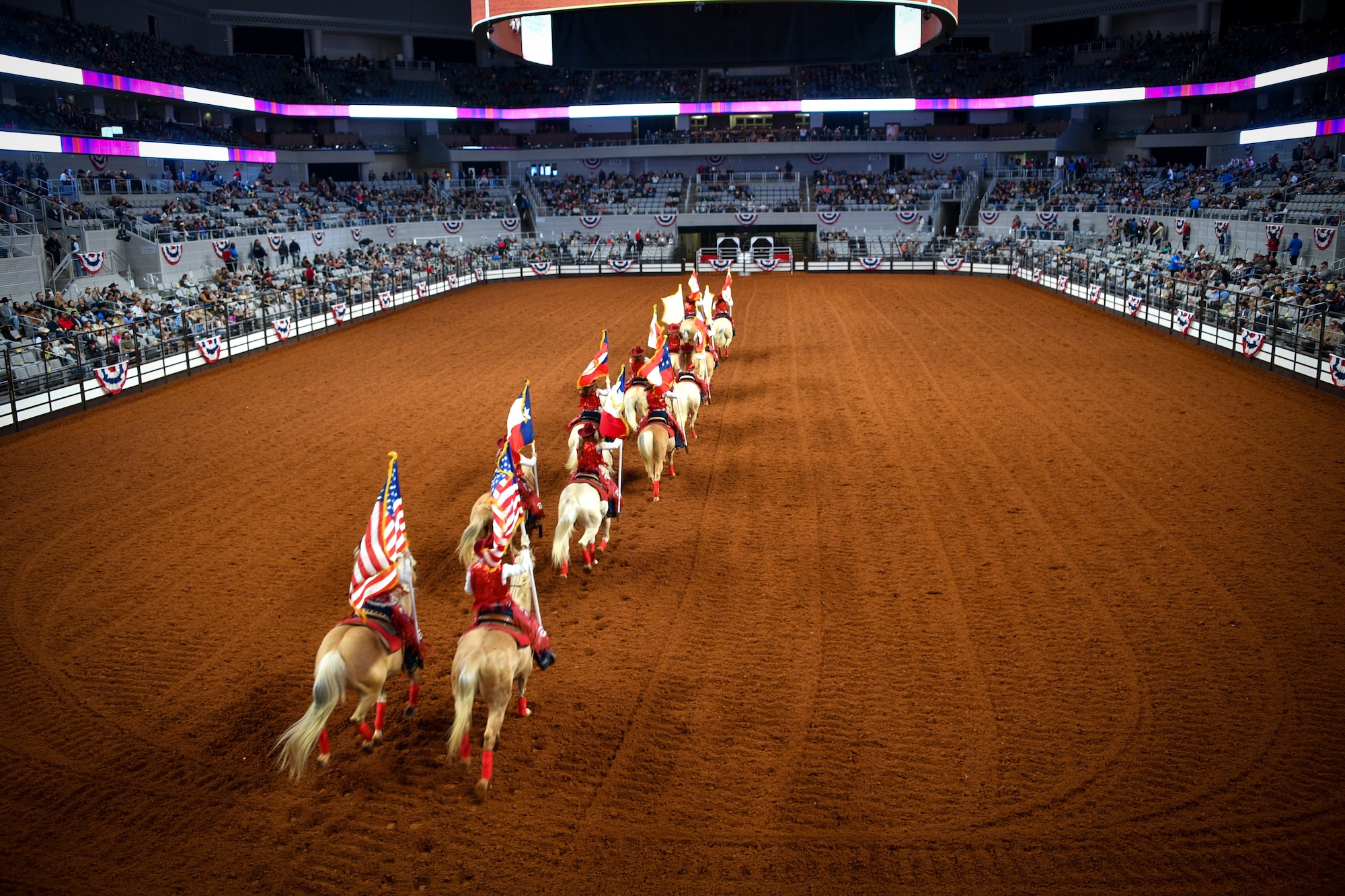 Riders bearing the six flags of Texas enter the arena during the Grand Entry at the Fort Worth Stock Show and Rodeo Dickies Arena, Jan. 31, 2022. The Grand Entry kicks off Military Appreciation Day at the FWSSR.(U.S. Air Force photo by Staff Sgt. Nije Hightower)