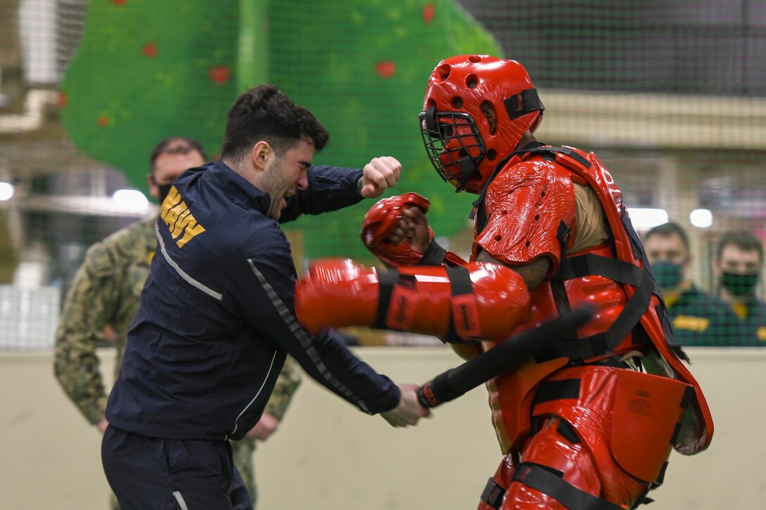 A sailor dressed in a red suit fights a fellow sailor during training.