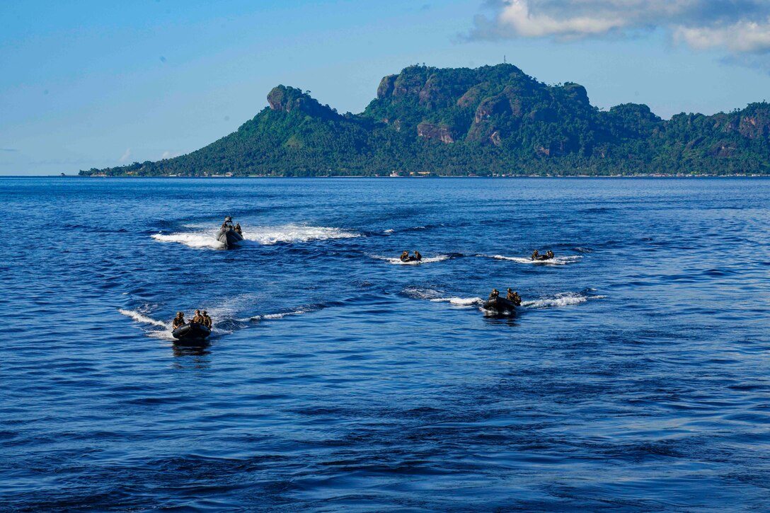Marines travel through waters in five inflatable boats.