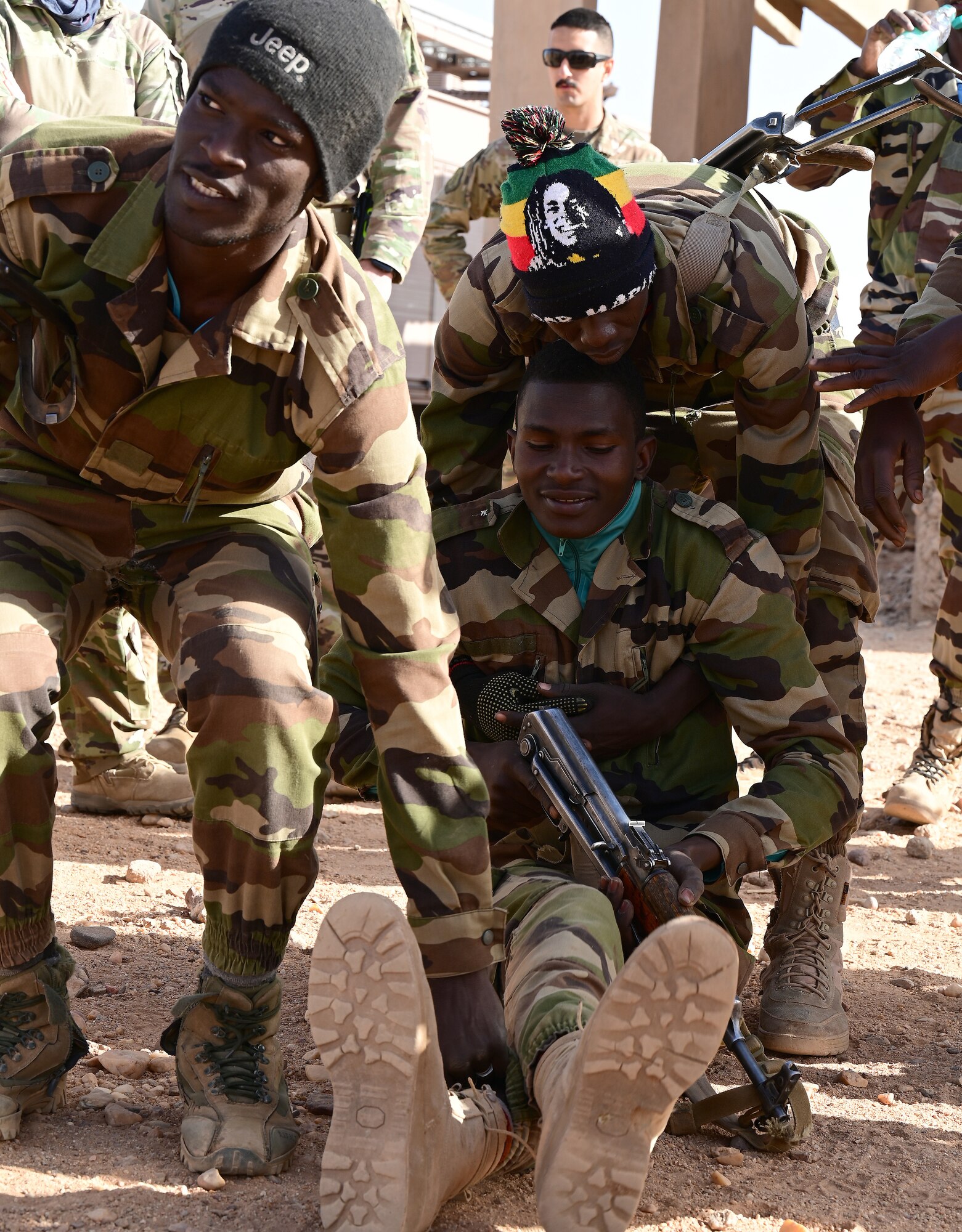 Three Nigerien Armed Forces (French language: Forces Armées Nigeriennes) members, practice a tactical carry taught to them by the 409th Expeditionary Security Forces Squadron air advisors and 724th Expeditionary Air Base Squadron firefighters  at Nigerien Air Base 201, Agadez, Niger, Jan. 21, 2022. The 409th ESFS hosted an eight-week course to train the FAN on various tactics such as combat lifesaving skills, weapon maneuvers, vehicle searches and patrol movements to enhance their ability to counter escalating violent extremism in the tri-border region of Niger, Burkina Faso, and Mali (U.S. Air Force photo by Tech. Sgt. Stephanie Longoria)