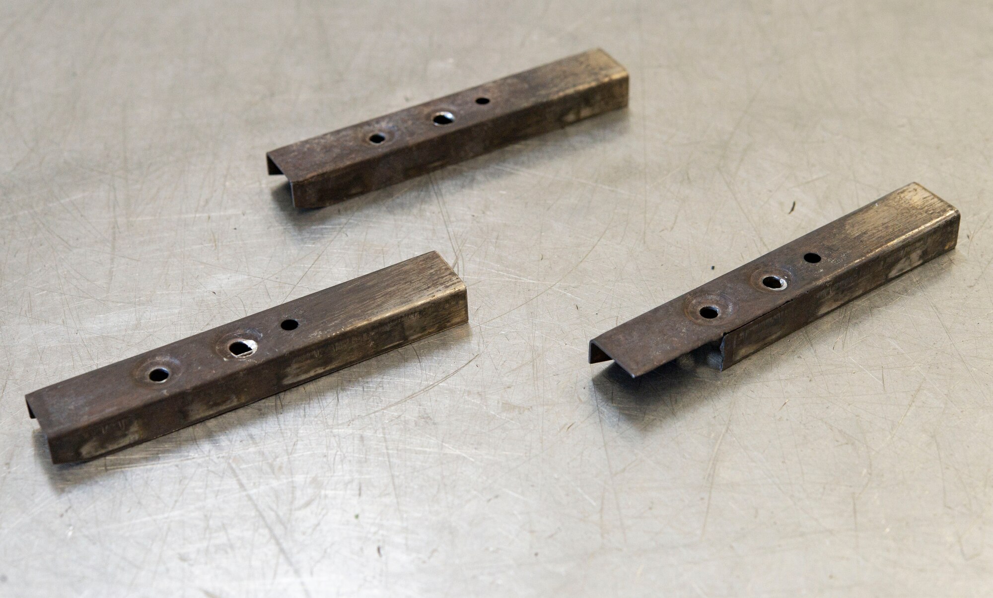 Damaged C-5M Super Galaxy brake torque tube assembly caps sit on a workbench after being removed during the repair of a brake assembly at Dover Air Force Base, Delaware, Nov. 10, 2021. The 436th Maintenance Squadron hydraulic shop is tasked to repair C-5M brake assemblies and return them back into the local supply inventory in minimal time, eliminating the need to outsource repairs. An orbital riveter is used to rivet new caps onto the brake torque tube. (U.S. Air Force photo by Roland Balik)