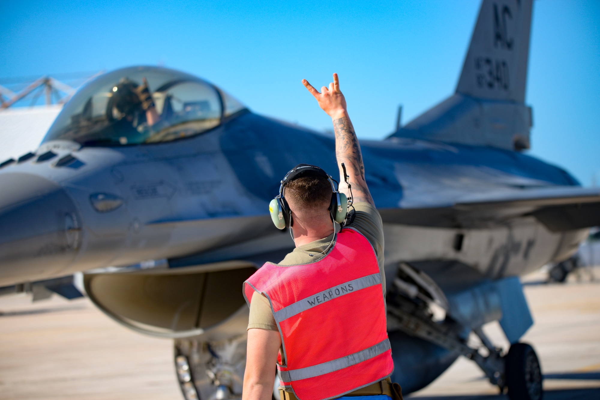 An image of load crew chief marshaling an F-16 Fighting Falcon