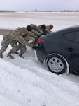Oklahoma National Guard members working with the Oklahoma Highway Patrol Stranded Motorist Assistance Recovery Team based in Vinita, Oklahoma push a vehicle out of a snowbank on the Will Rogers Turnpike near Vinita, Oklahoma, Feb. 3, 2022.