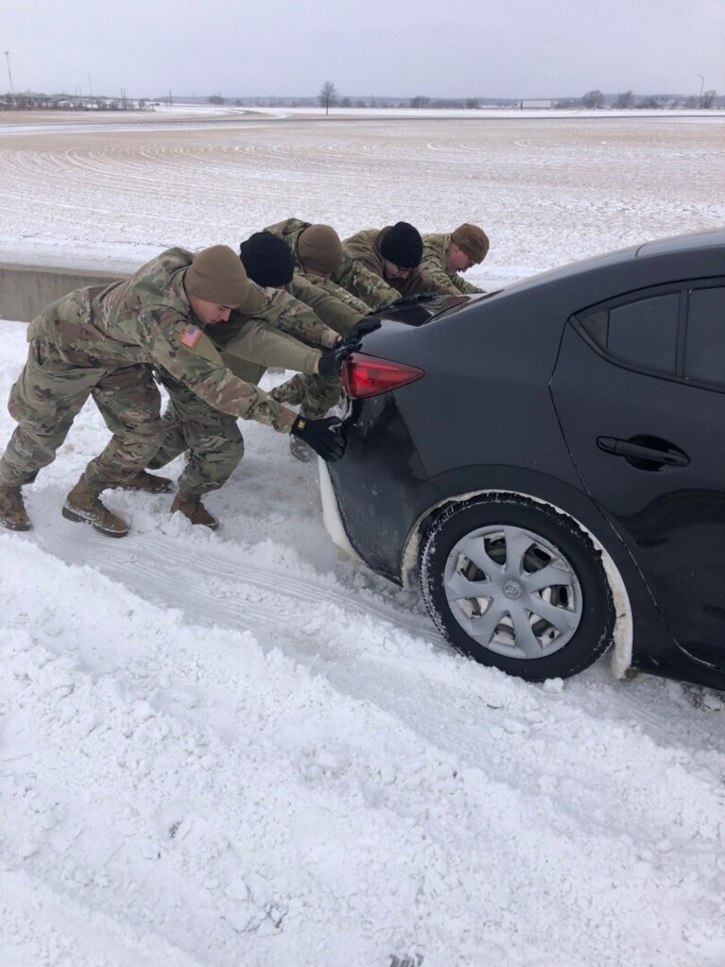 Oklahoma National Guard members working with the Oklahoma Highway Patrol Stranded Motorist Assistance Recovery Team based in Vinita, Oklahoma push a vehicle out of a snowbank on the Will Rogers Turnpike near Vinita, Oklahoma, Feb. 3, 2022.