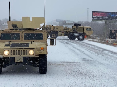 Oklahoma National Guard members assigned to the Oklahoma Highway Patrol's Durant Stranded Motorist Assistance Recovery Team help OHP block off a highway while a civilian wrecker recovers a semi truck that slid off the road in Calera, Oklahoma, Feb. 3, 2022.