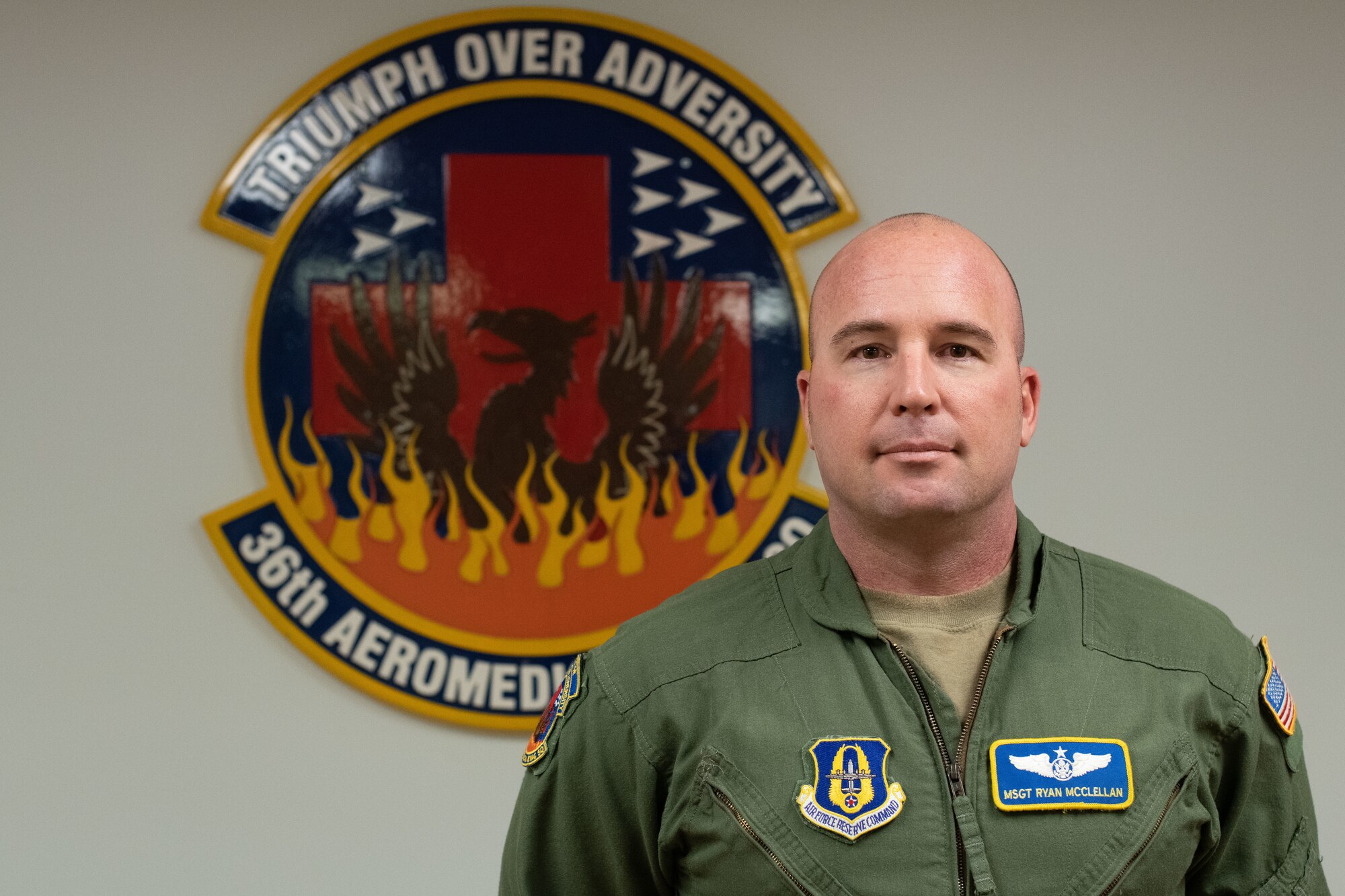 MSgt. McClellan stands in front of the 36th Aeromedical Evacuation Squadron logo. It says Triumph over adversity/36th AES.