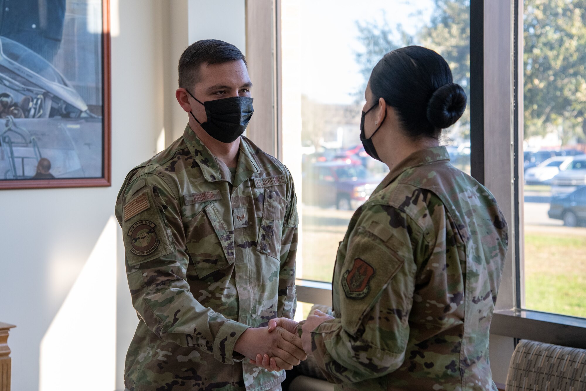 An Airman shakes an Airman's hand.