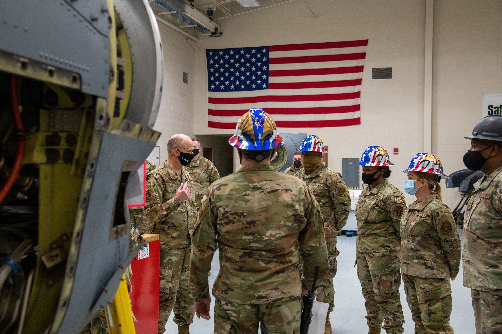 A group of Airmen listen to Maj. Gen. Larson. C-130J engine in the foreground.