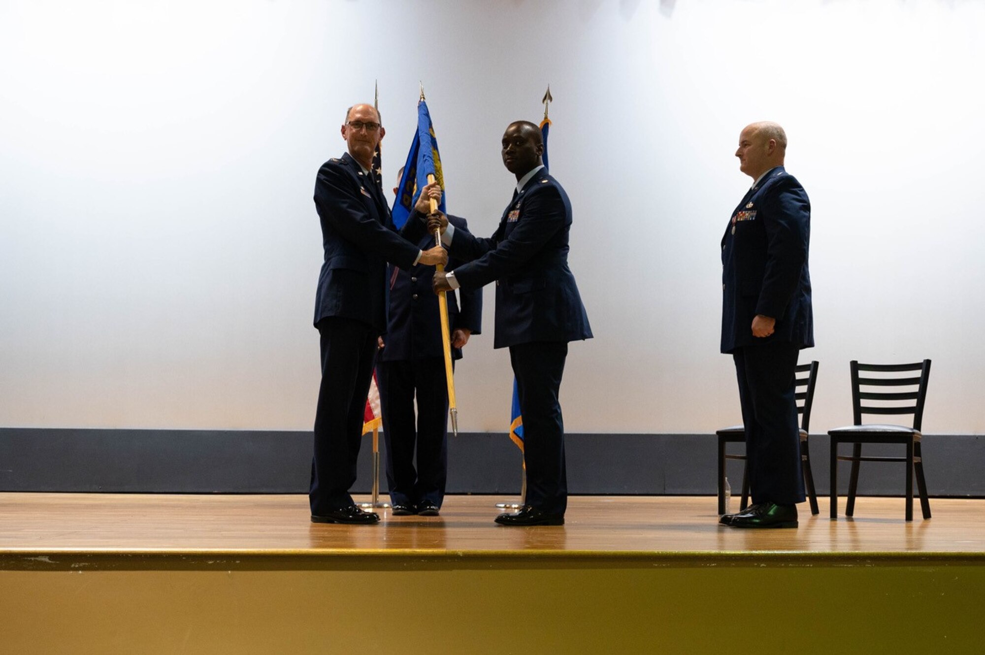 People stand on stage and hand flag to one another