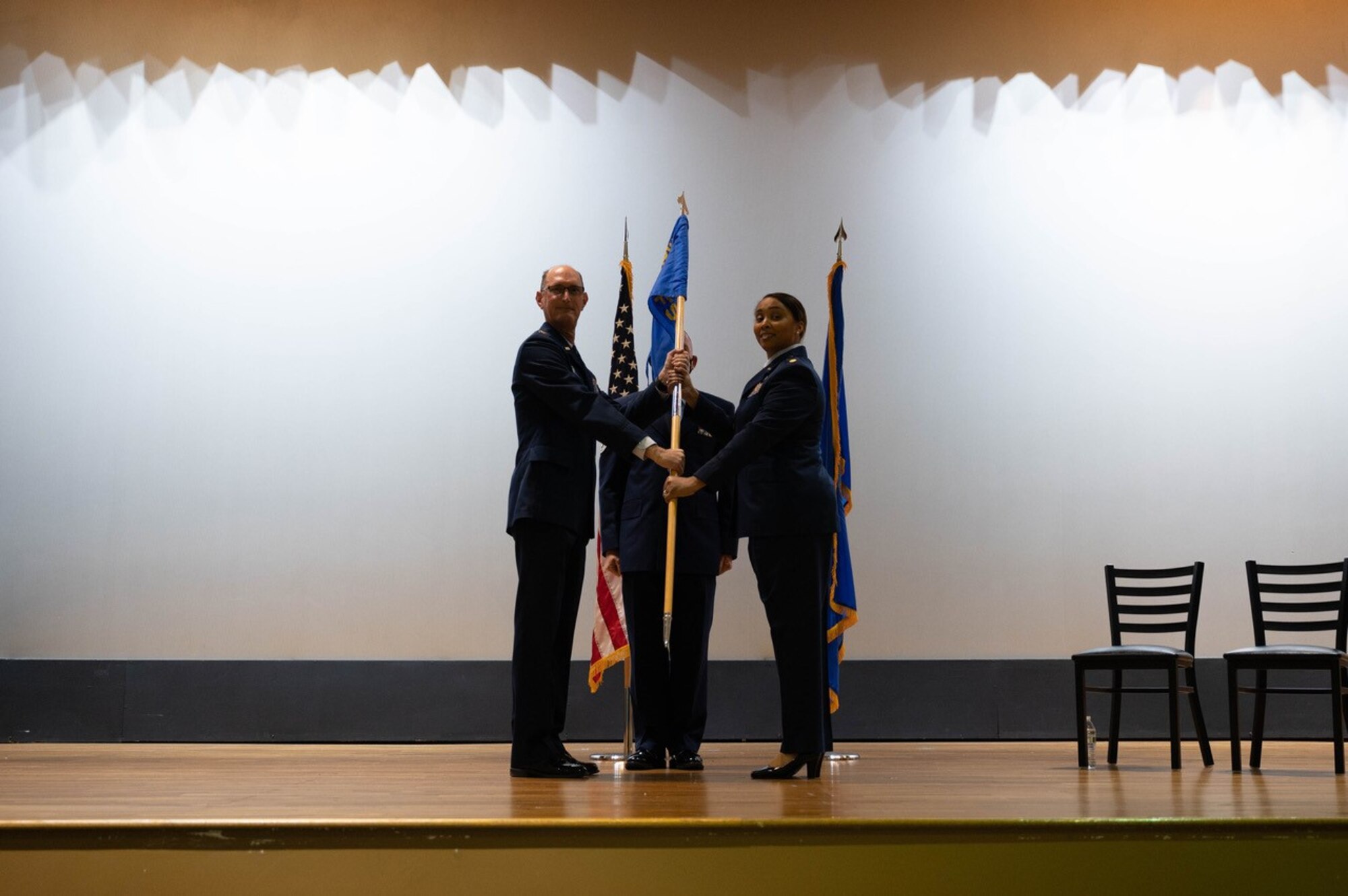 People stand on stage and hand flag to one another