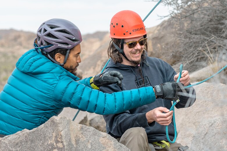 Daniel Johnson, a rock-climbing guide with Climb Life, shows U.S. Navy veteran Alen Smitkarako how to secure his harness during a LiboRisk rock climbing event at Joshua Tree National Park, Joshua Tree, California on Jan. 29, 2022. LiboRisk, founded by U.S. Marine veteran Jessica Quezada, is a travel community to bring active duty and veteran service members together to further build camaraderie outside the military and expose attendees to new, positive experiences. (U.S. Marine Corps photo by Staff Sgt. Kelsey Dornfeld)