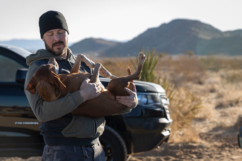 U.S. Marine Corps veteran Justin Blazejewski holds his service dog, Bria, during a LiboRisk event at Joshua Tree National Park, Joshua Tree, California on Jan. 29, 2022. LiboRisk, founded by U.S. Marine veteran Jessica Quezada, is a travel community to bring active duty and veteran service members together to further build camaraderie outside the military and expose attendees to new, positive experiences. (U.S. Marine Corps photo by Staff Sgt. Kelsey Dornfeld)