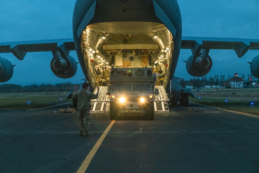 A large aircraft sits on the tarmac with its ramp down.