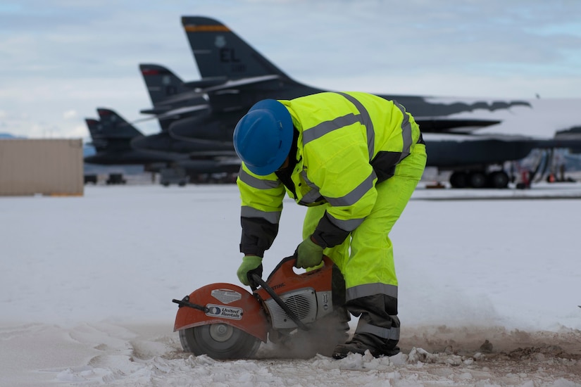 A person cuts asphalt with a machine.