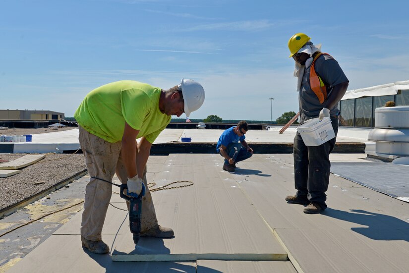 Men install insulation panels on a roof.