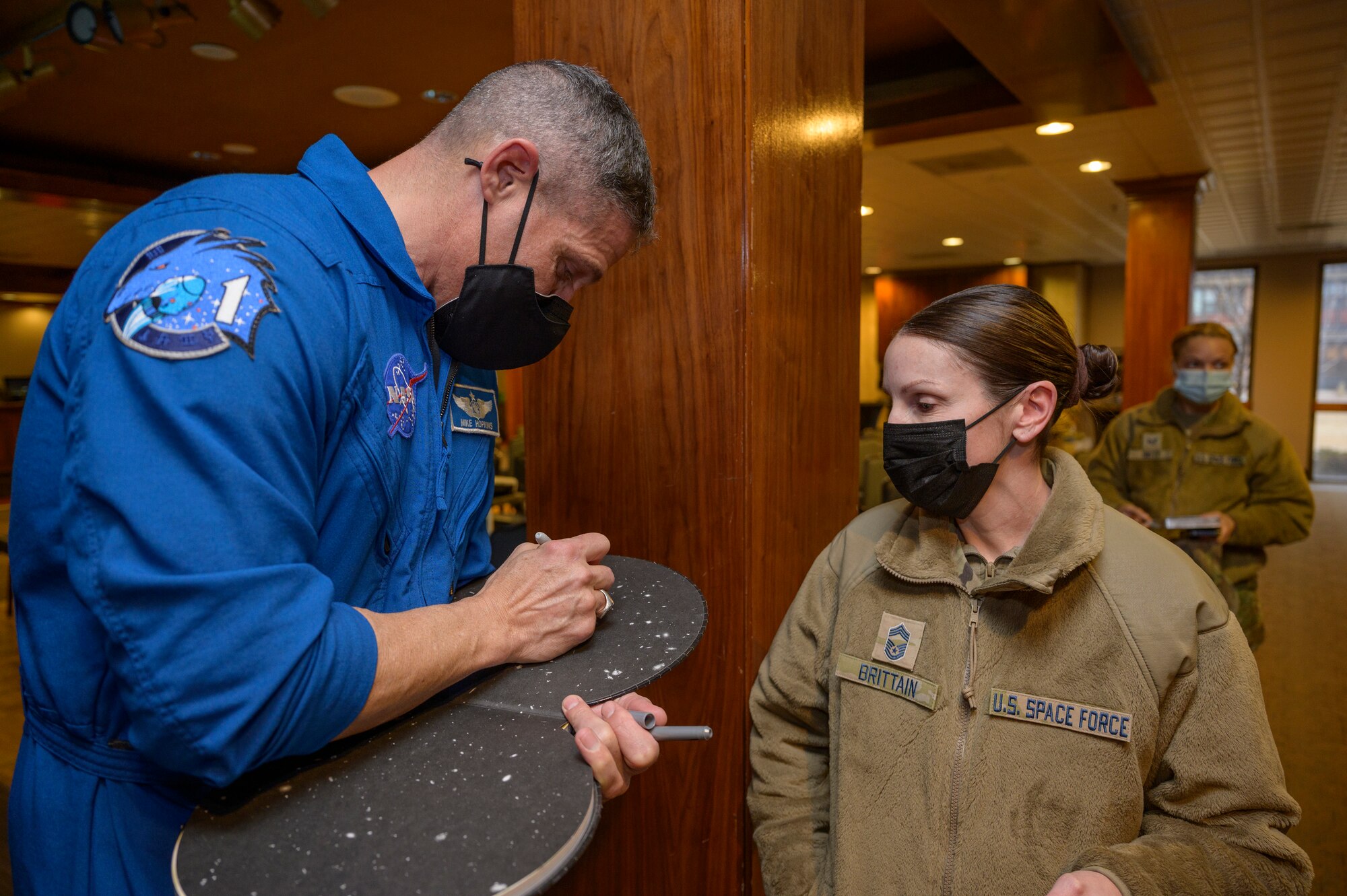 U.S. Space Force Col. Mike Hopkins, NASA astronaut, signs a children’s astronomy book for U.S. Space Force Chief Master Sgt. April Brittain, Space Delta 2 – Space Domain Awareness superintendent, following a presentation at the Hub on Peterson Space Force Base, Colorado, Jan. 25, 2022. Hopkins, the first astronaut to transfer into the Space Force, spoke with Airmen, Guardians, families and civilians about his personal experiences in space with the hope of inspiring future Guardians and astronauts. (U.S. Space Force photo by Paul Honnick)