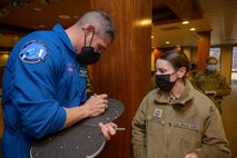 U.S. Space Force Col. Mike Hopkins, NASA astronaut, signs a children’s astronomy book for U.S. Space Force Chief Master Sgt. April Brittain, Space Delta 2 – Space Domain Awareness superintendent, following a presentation at the Hub on Peterson Space Force Base, Colorado, Jan. 25, 2022. Hopkins, the first astronaut to transfer into the Space Force, spoke with Airmen, Guardians, families and civilians about his personal experiences in space with the hope of inspiring future Guardians and astronauts. (U.S. Space Force photo by Paul Honnick)