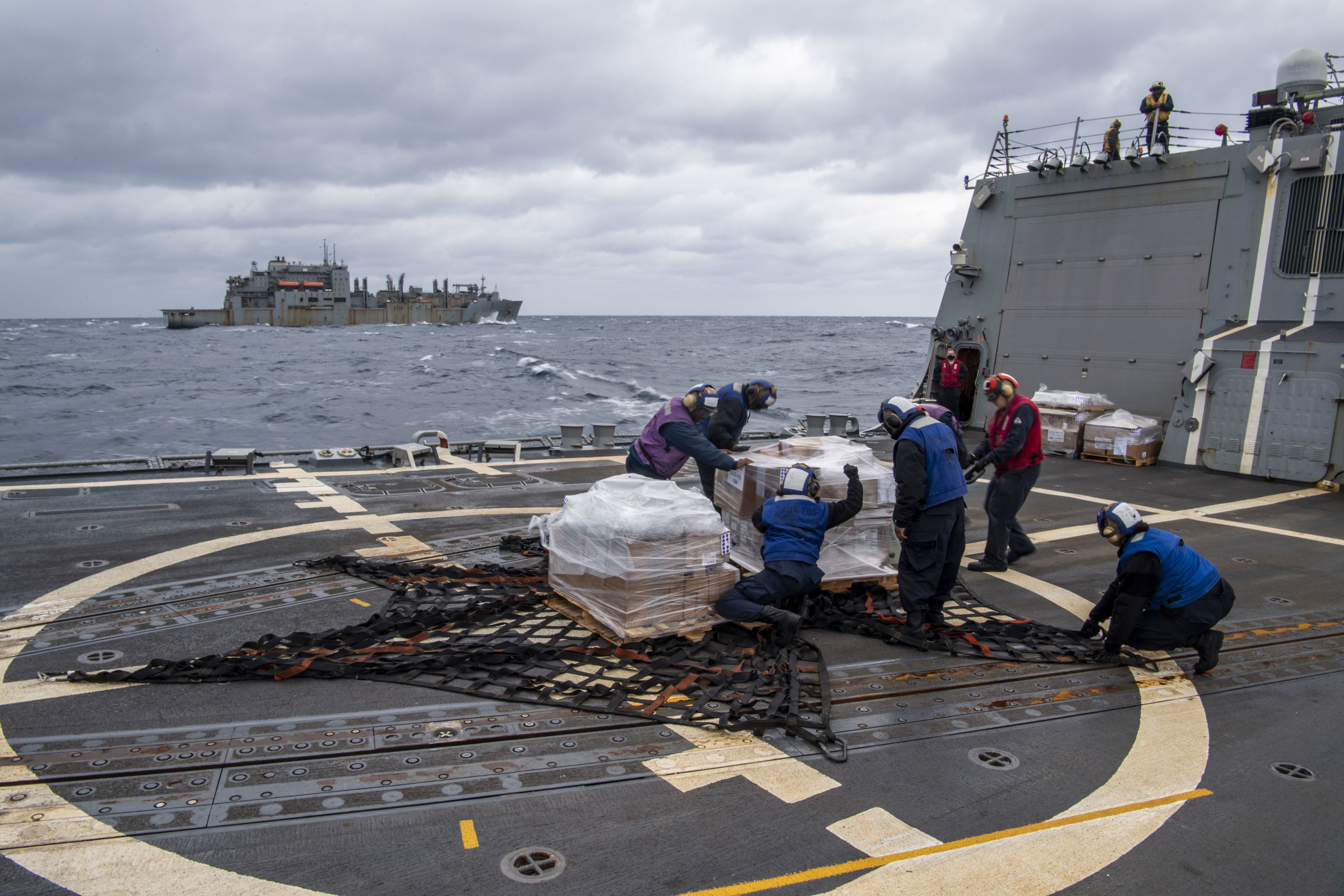 Sailors assigned to the Arleigh Burke-class guided-missile destroyer USS Dewey (DDG 105) recover supplies dropped off from a MH-60R helicopter assigned to Helicopter Maritime Strike Squadron (HSM) 51 during a vertical replenishment with the Military Sealift Command dry cargo and ammunition ship USNS Alan Shepard (T-AKE 3) while participating in Exercise Noble Fusion.