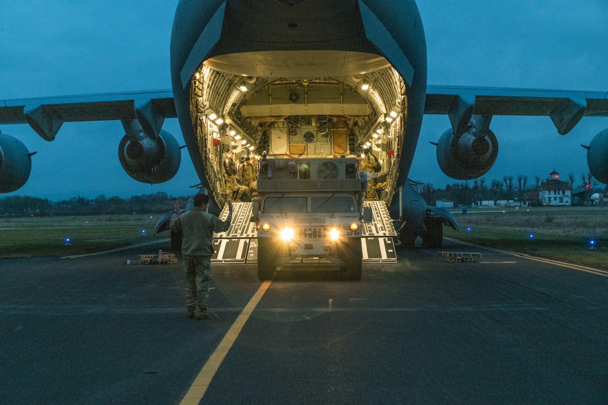 A large aircraft sits on the tarmac with its ramp down.