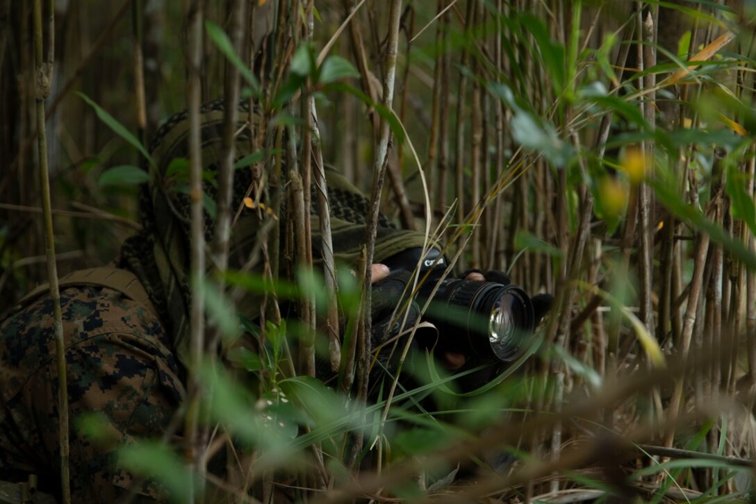 Cpl. Jacob Wright, a scout sniper, with Battalion Landing Team 1/5, 31st Marine Expeditionary Unit (MEU) captures imagery of key road terrain during a two-day route reconnaissance mission at the Jungle Warfare Training Center in Okinawa, Japan, Jan. 12, 2022. Scout snipers play an integral part in the Stand in Force Concept operating as the eyes and ears of the ground force commander, allowing for a more efficient decision making process. The 31st MEU, the Marine Corps' only continuously forward-deployed MEU, provides a flexible and lethal force ready to perform a wide range of military operations as the premiere crisis response force in the Indo-Pacific region. (U.S. Marine Corps photo by Lance Cpl. Christopher W. England)
