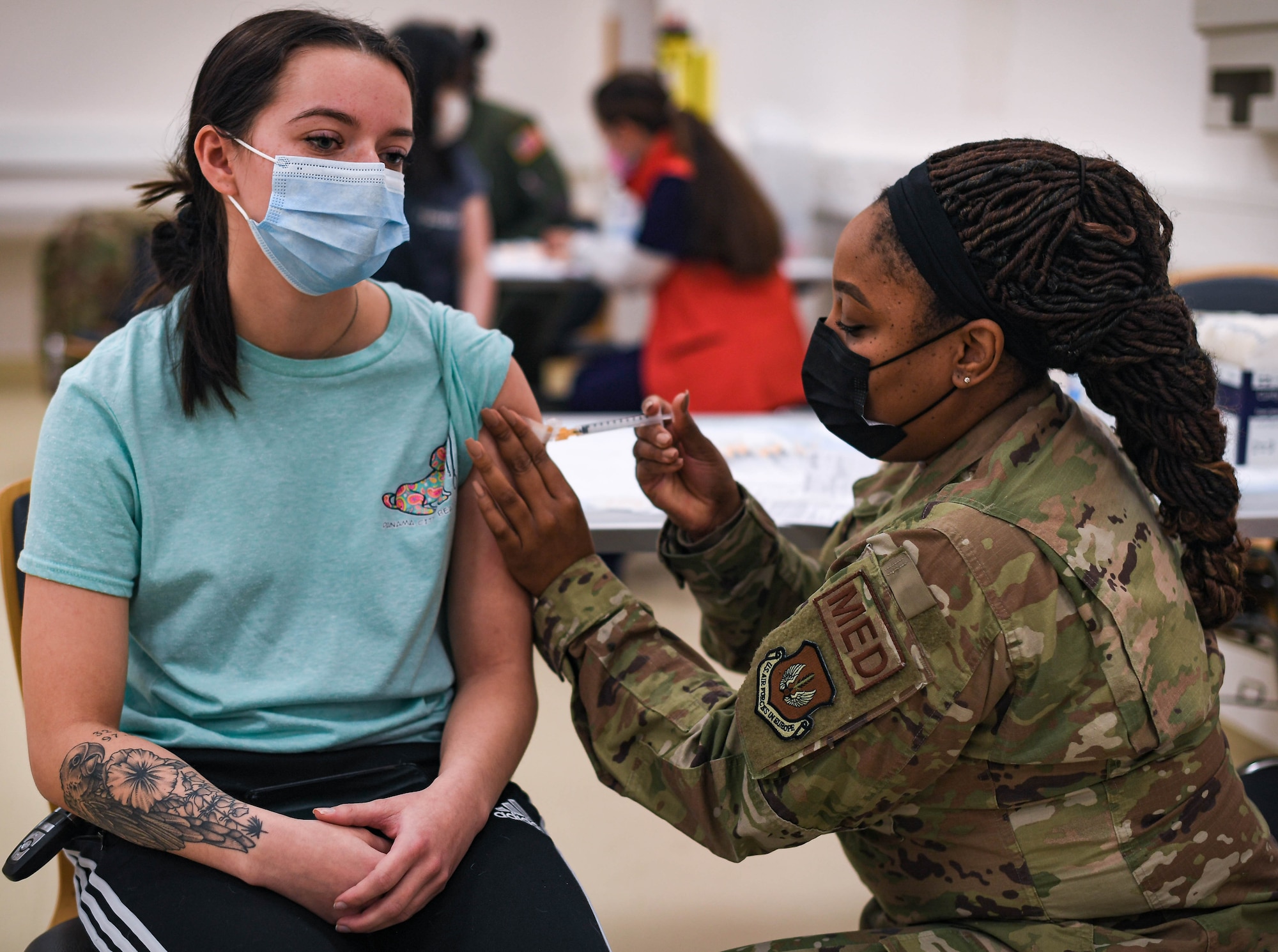 U.S. Air Force Tech. Sgt. Latasha Smith, 86th Operational Medical Readiness Squadron warrior medicine clinic flight chief, right, administers the Moderna COVID-19 booster shot to Airman 1st Class Trinity Duncan,  569th U.S. Forces Police Squadron security police, left, at Ramstein Air Base, Germany, Jan. 28, 2022. Since Jan. 4, 2021, Smith has been the continual point of contact for all of the 86th Medical Group COVID-19 vaccine lines, directly overseeing the schedule, patient administration and treatment rendered by 48 medics. (U.S. Air Force photo by Airman 1st Class Jared Lovett)