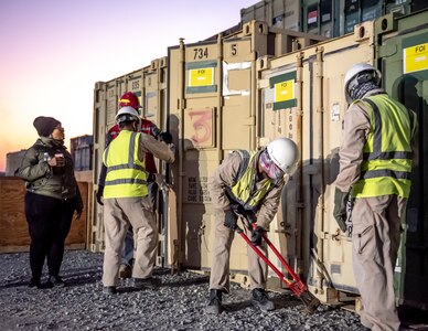 Coalition civilian contractors inspect an equipment container sent from locations in Iraq to Camp Arifjan, Kuwait, Jan. 19, 2022. The equipment was received as part of a strategic effort to recycle and reapportion unused equipment as Combined Joint Task Force – Operation Inherent Resolve continues its advise, assist, and enable mission. (U.S. Air National Guard photo by Staff Sgt. Chloe Ochs)