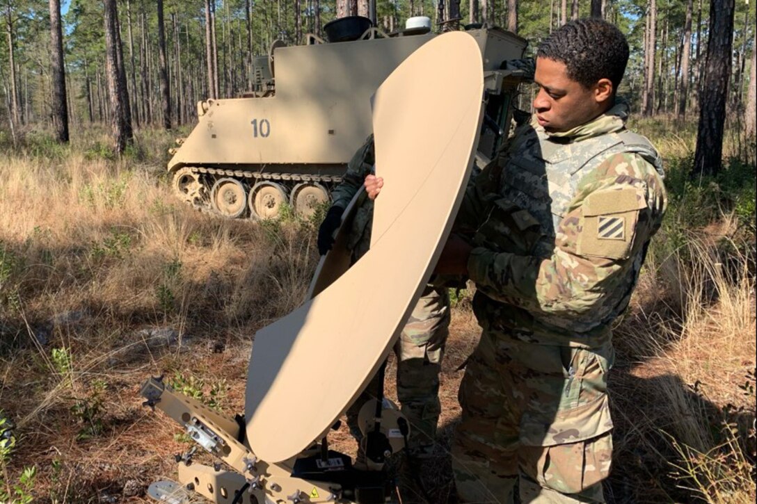 A soldier sets up a satellite dish.
