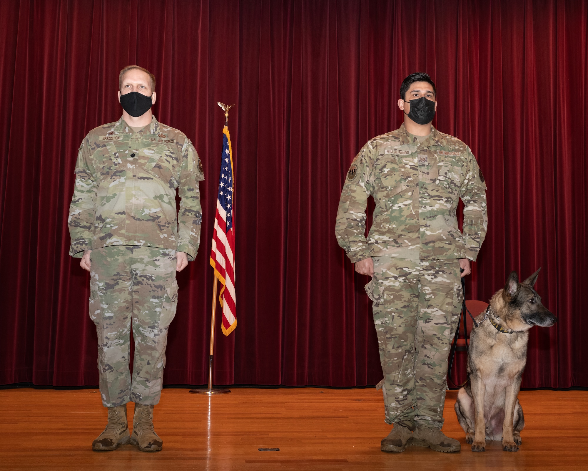 U.S. Air Force Lt. Col. Sproston, 509th Security Forces Squadron Commander and U.S. Air Force Staff Sgt. Alex Villalpando, 509th Security Forces military working dog handler, prepare to present U.S. Air Force MWD Stiffler with the Meritorious Service Medal during Stiffler's retirement ceremony at the base theater on Whiteman Air Force Base Feb. 4, 2022. Military working dogs provide a valuable force multiplier to aid in security and readiness within our units. (U.S. Air Force photo by Airman 1st Class Bryson Britt)