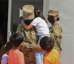 Spc. Kiyana Santamaria, left, an Army motor transport operator, and Spc. Jessica Koroma, a religious affairs specialist with 377th Transportation Company, 142nd Combat Sustainment Support Battalion, 1st Armored Division, interacts with Afghan children while serving as a member of a female engagement team in support of Operation Allies Welcome at Fort Bliss’ Doña Ana Complex in New Mexico, Sept. 11, 2021. FETs assist female Afghan guests with navigating in processing procedures and other issues and concerns they may have. The Department of Defense, through U.S. Northern Command, and in support of the Department of Homeland Security, is providing transportation, temporary housing, medical screening, and general support for at least 50,000 Afghan evacuees at suitable facilities, in permanent or temporary structures, as quickly as possible. This initiative provides Afghan personnel essential support at secure locations outside Afghanistan. (U.S. Army photo by Sgt. Christina Westover, 24th Theater Public Affairs Support Element)