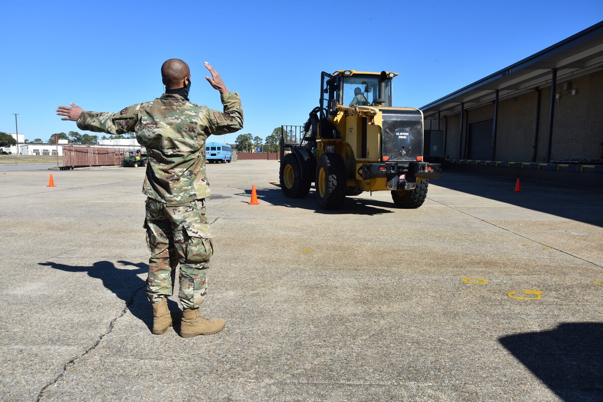 An Airman directs someone driving a forklift to the left