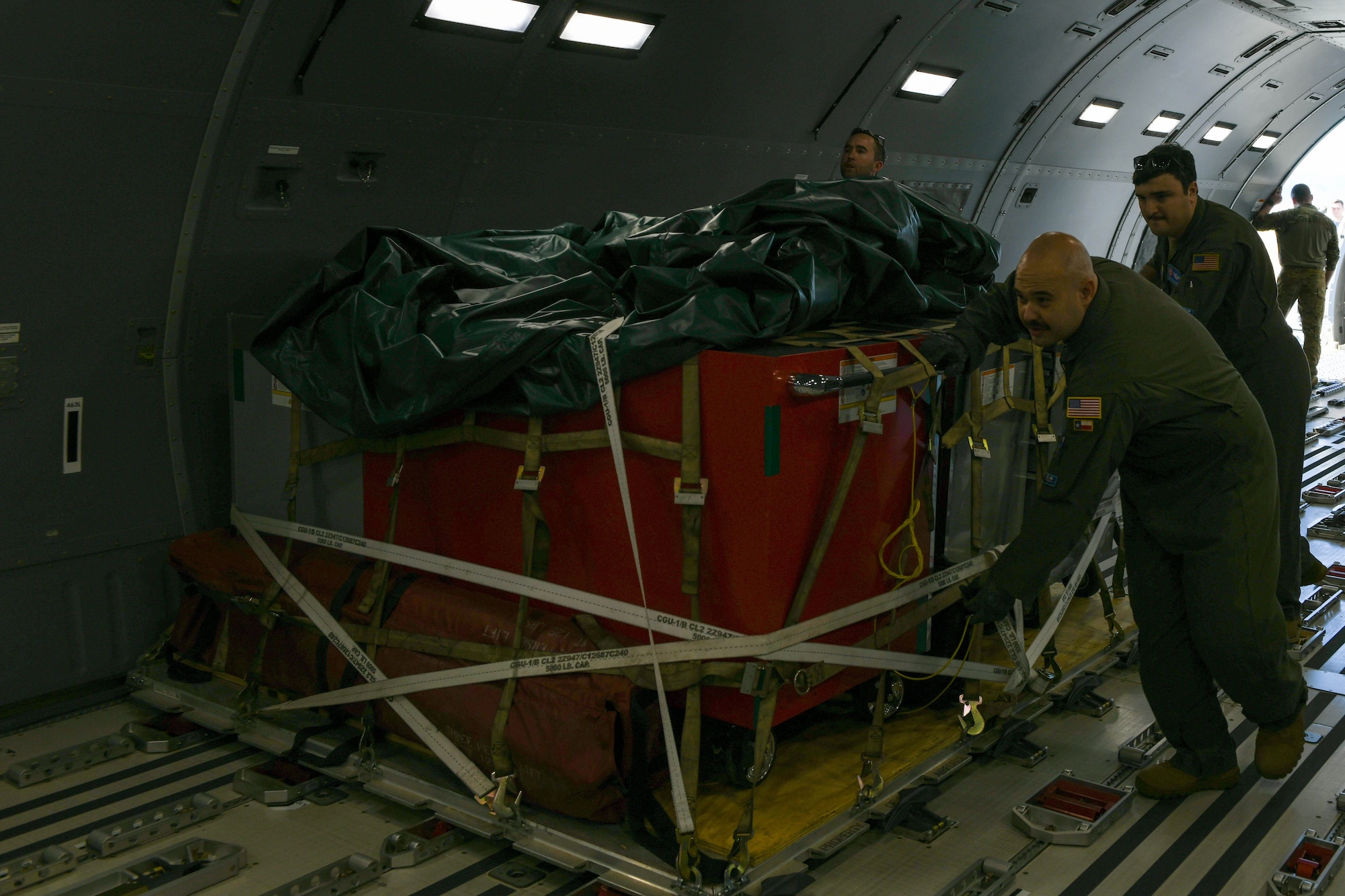 U.S. Air Force Tech. Sgt. Ian Sweaney, 56th Air Refueling Squadron (ARS) loadmaster, Tech. Sgt. Ezekiel Brito, 56th ARS loadmaster, and Staff Sgt. Anthony Velasquez, 56th ARS loadmaster, push cargo on a KC-46 Pegasus on Luke Air Force Base, Arizona, Jan. 27, 2022. The KC-46 was loaded with roughly 30,000 pounds of cargo from the 56th Operations Group. (U.S. Air Force photo by Airman 1st Class Trenton Jancze)